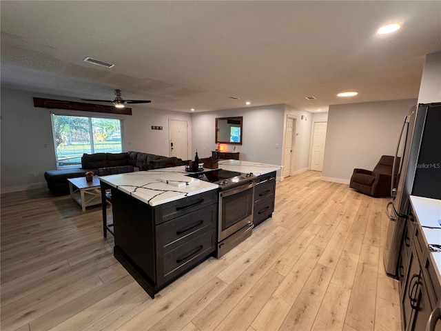 kitchen featuring stainless steel range with electric stovetop, light hardwood / wood-style flooring, a breakfast bar area, and a kitchen island