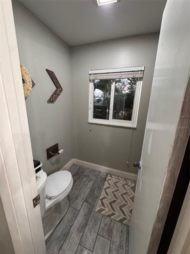 bathroom featuring toilet, wood tiled floor, and baseboards