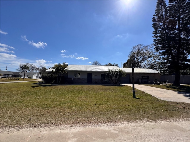 ranch-style home with metal roof, concrete driveway, a front lawn, and fence