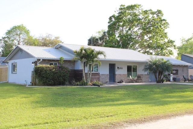 ranch-style home featuring metal roof, a front lawn, and brick siding