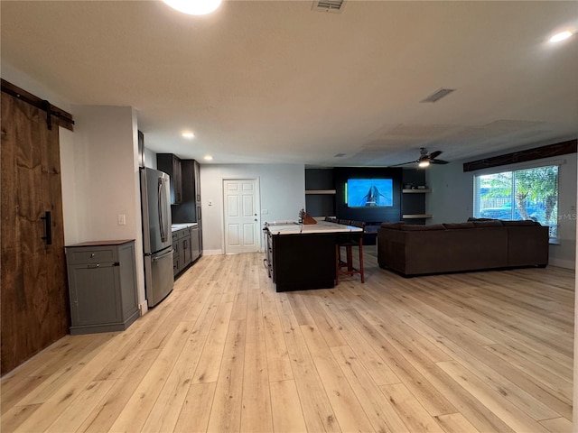 kitchen with light wood-style floors, a barn door, open floor plan, and freestanding refrigerator