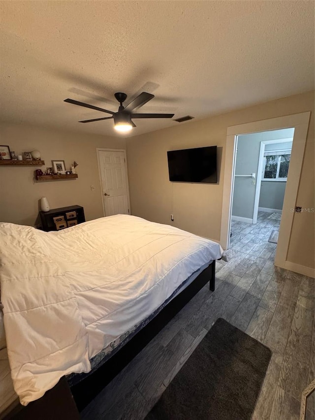 bedroom featuring baseboards, a textured ceiling, visible vents, and wood finished floors