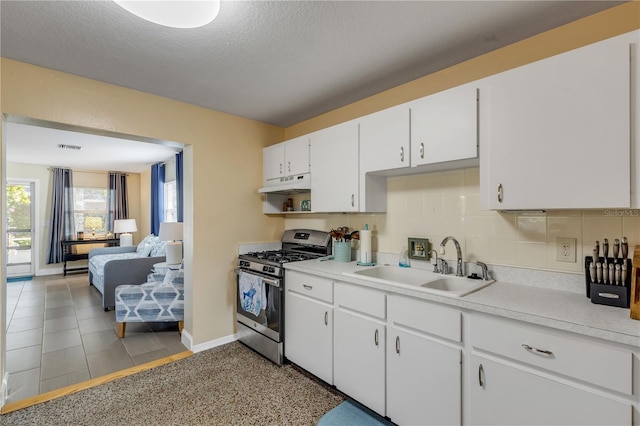 kitchen with sink, stainless steel gas range, backsplash, a textured ceiling, and white cabinets