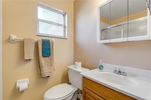 bathroom with walk in shower, vanity, and toilet