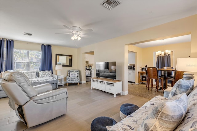 living room with ceiling fan with notable chandelier