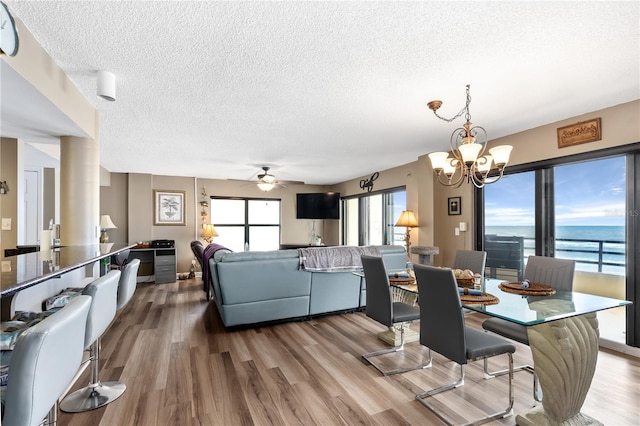 dining room featuring hardwood / wood-style flooring, ceiling fan with notable chandelier, and a textured ceiling