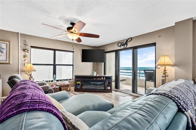 living room featuring hardwood / wood-style flooring, ceiling fan, and a textured ceiling