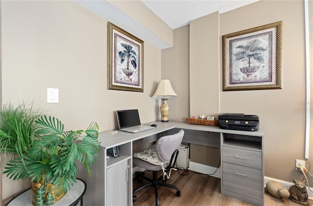 home office featuring built in desk, a textured ceiling, and light wood-type flooring