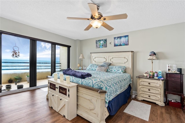 bedroom featuring ceiling fan, dark hardwood / wood-style floors, a textured ceiling, and a water view