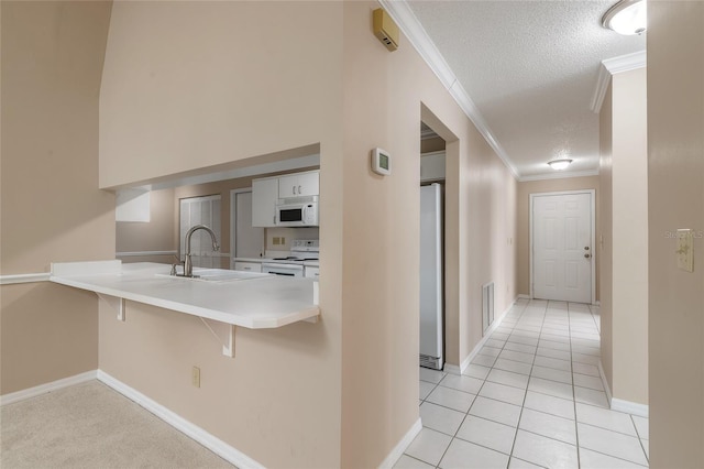 hall featuring crown molding, sink, light tile patterned flooring, and a textured ceiling