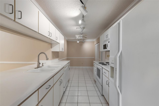 kitchen with sink, white appliances, light tile patterned floors, and white cabinets