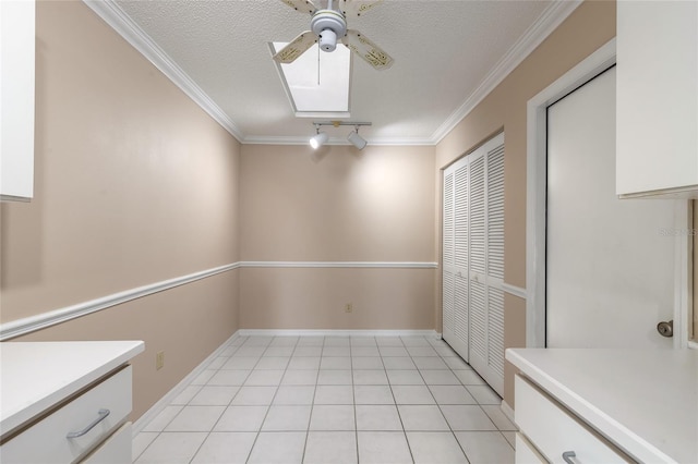 interior space with crown molding, light tile patterned floors, ceiling fan, and a textured ceiling