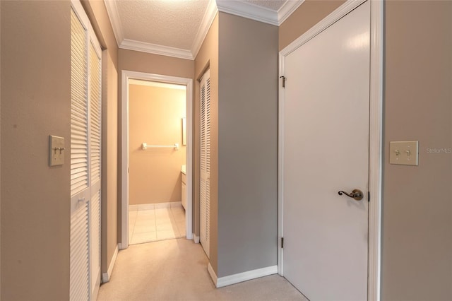 hallway with light colored carpet, ornamental molding, and a textured ceiling