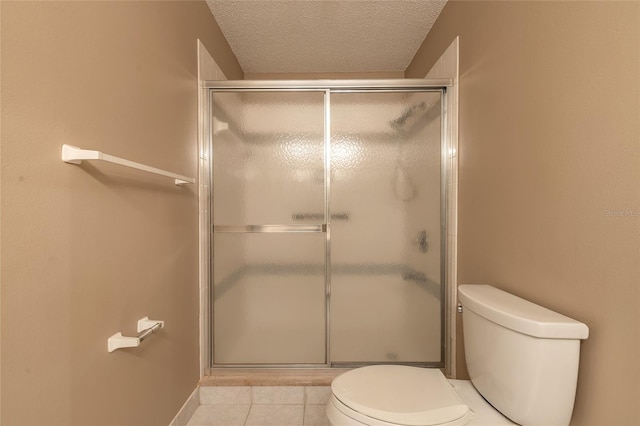 bathroom featuring walk in shower, tile patterned floors, toilet, and a textured ceiling