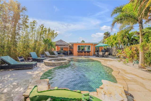 view of pool featuring a patio, an outdoor fire pit, fence, a pool with connected hot tub, and a gazebo