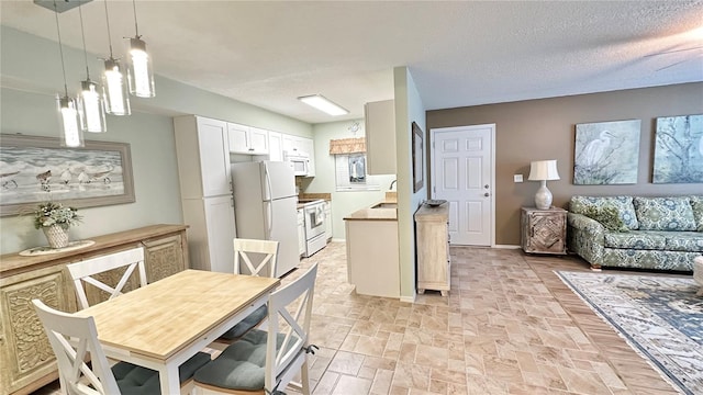 kitchen with decorative light fixtures, white cabinetry, sink, white appliances, and a textured ceiling