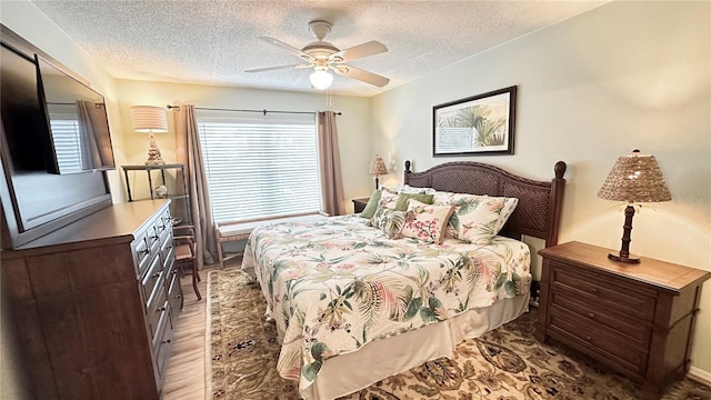 bedroom with multiple windows, ceiling fan, wood-type flooring, and a textured ceiling