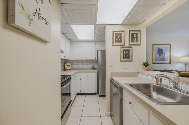 kitchen with light tile patterned flooring, sink, white cabinetry, appliances with stainless steel finishes, and decorative backsplash