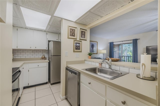 kitchen with sink, stainless steel appliances, tasteful backsplash, white cabinets, and light tile patterned flooring