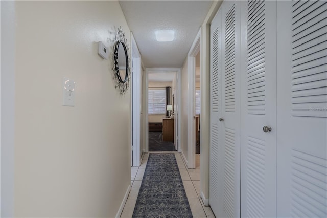 corridor featuring light tile patterned floors and a textured ceiling