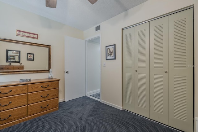 unfurnished bedroom featuring ceiling fan, dark carpet, a closet, and a textured ceiling