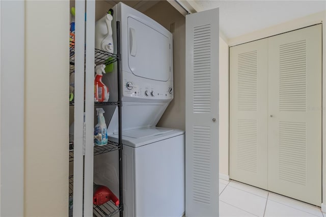 clothes washing area with stacked washing maching and dryer and light tile patterned floors