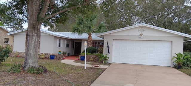 ranch-style home featuring metal roof, concrete driveway, an attached garage, and stucco siding