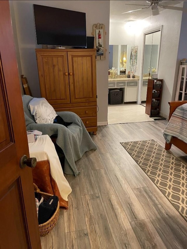 bedroom featuring baseboards, ensuite bathroom, and light wood-style floors