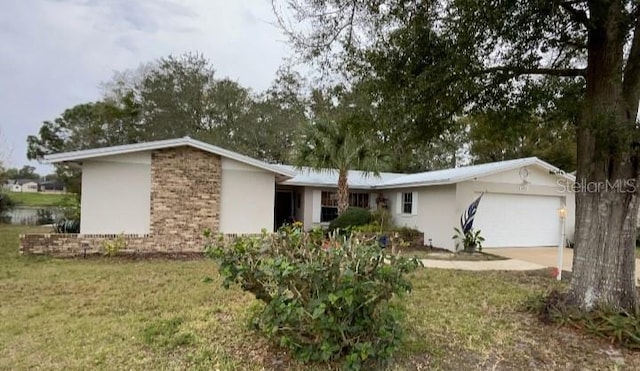 single story home featuring a garage, driveway, brick siding, and a front yard