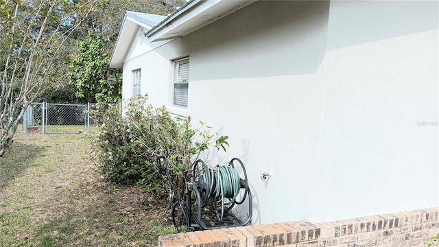 view of side of property with stucco siding and fence