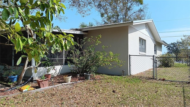 view of side of property with a gate, fence, and stucco siding