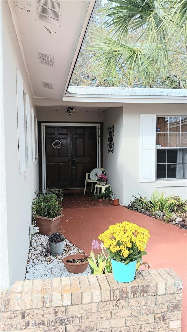 entrance to property featuring visible vents and stucco siding