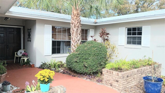 view of exterior entry with stucco siding and metal roof