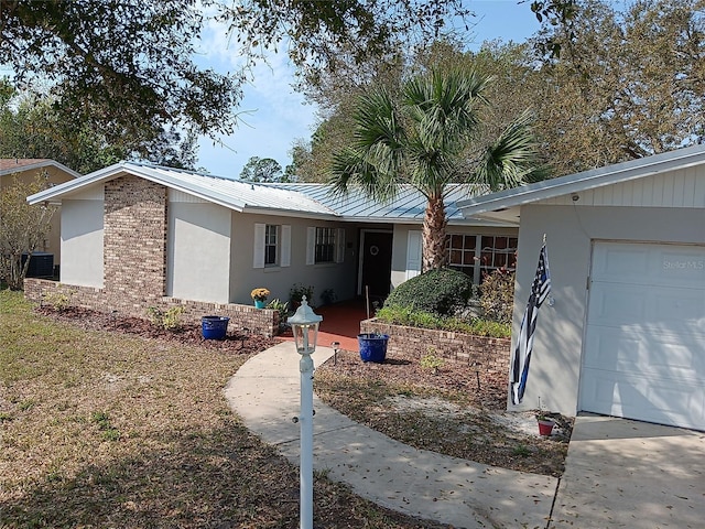 ranch-style house featuring brick siding, stucco siding, an attached garage, and metal roof