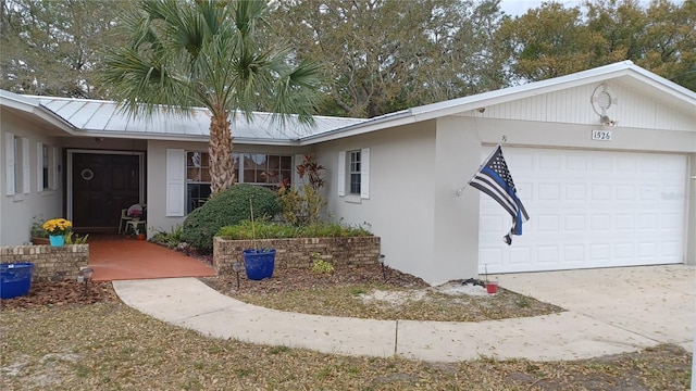 view of front of house with stucco siding, an attached garage, and metal roof