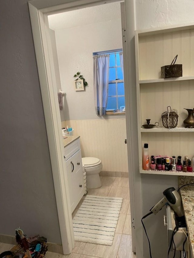 bathroom featuring vanity, toilet, and wainscoting