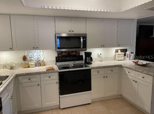 kitchen with light tile patterned floors, visible vents, electric range, white cabinetry, and stainless steel microwave