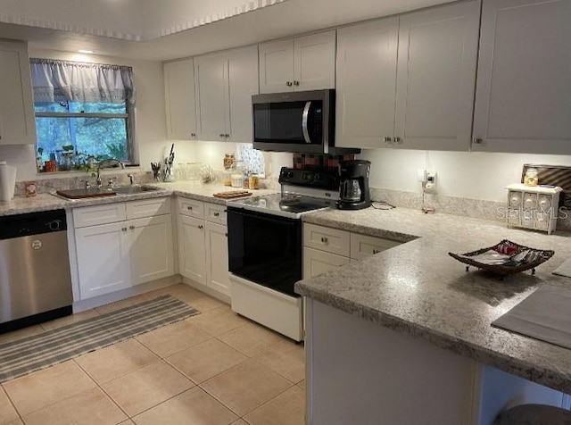 kitchen featuring white cabinets, light stone counters, appliances with stainless steel finishes, and a sink