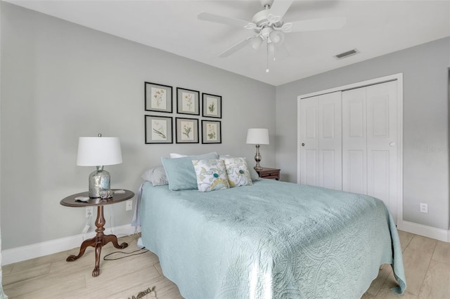 bedroom featuring wood finished floors, a ceiling fan, visible vents, baseboards, and a closet