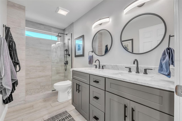 bathroom featuring vanity, toilet, and a tile shower