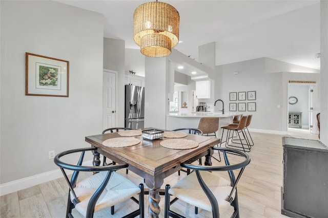 dining area with an inviting chandelier, sink, and light wood-type flooring