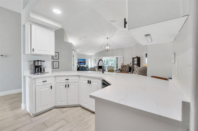 kitchen featuring vaulted ceiling, sink, white cabinets, and light wood-type flooring