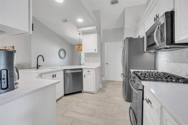 kitchen with appliances with stainless steel finishes, sink, pendant lighting, and white cabinets