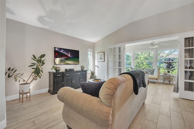 living area featuring lofted ceiling, light wood finished floors, and baseboards