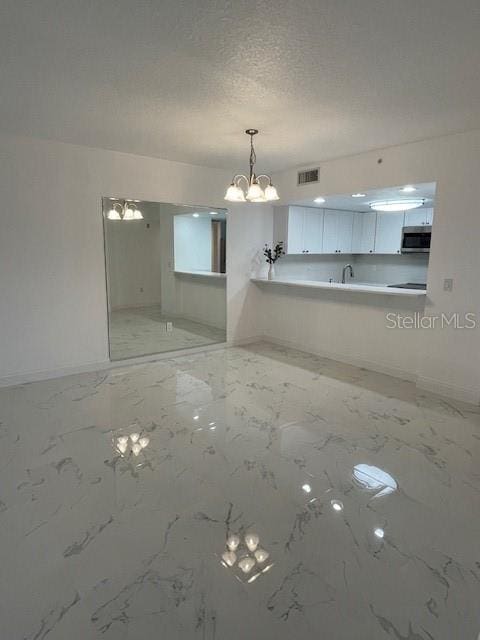 interior space featuring sink, a chandelier, and a textured ceiling