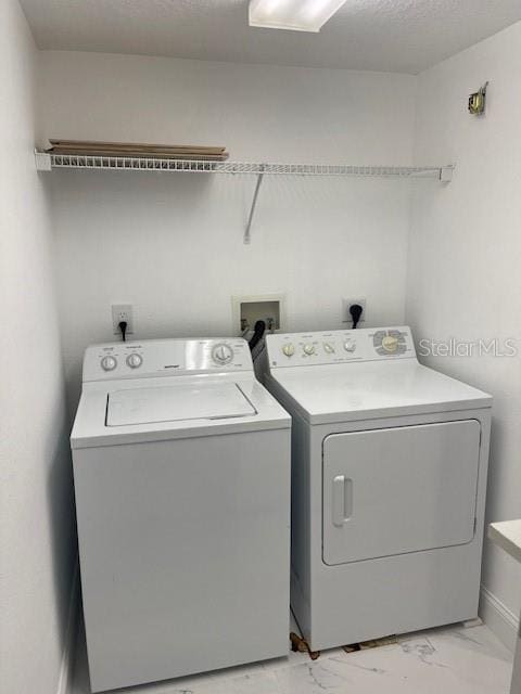 clothes washing area featuring washing machine and clothes dryer and a textured ceiling