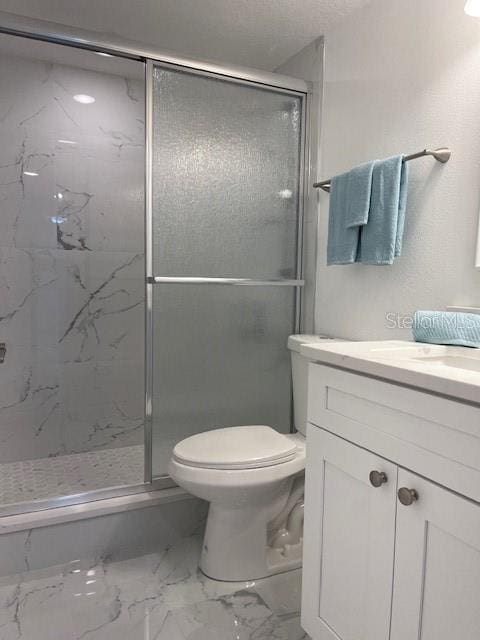 bathroom featuring vanity, a shower with shower door, and toilet