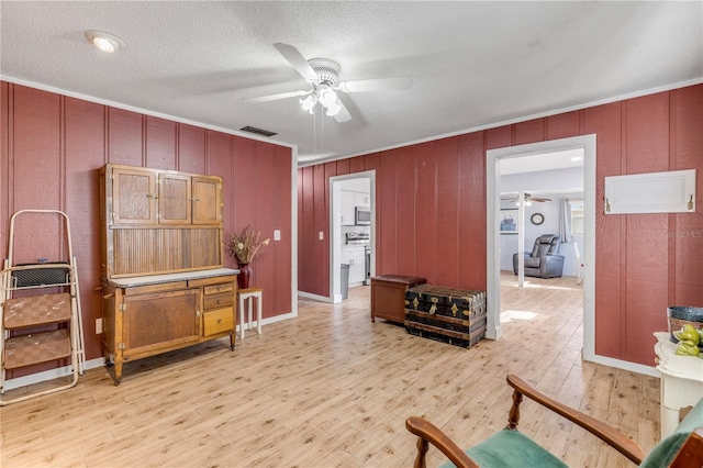 living area with crown molding, light hardwood / wood-style flooring, a textured ceiling, and ceiling fan