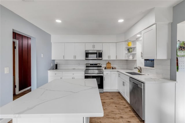 kitchen featuring white cabinetry, stainless steel appliances, sink, and light stone counters