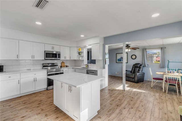 kitchen featuring stainless steel appliances, a center island, light wood-type flooring, and white cabinets